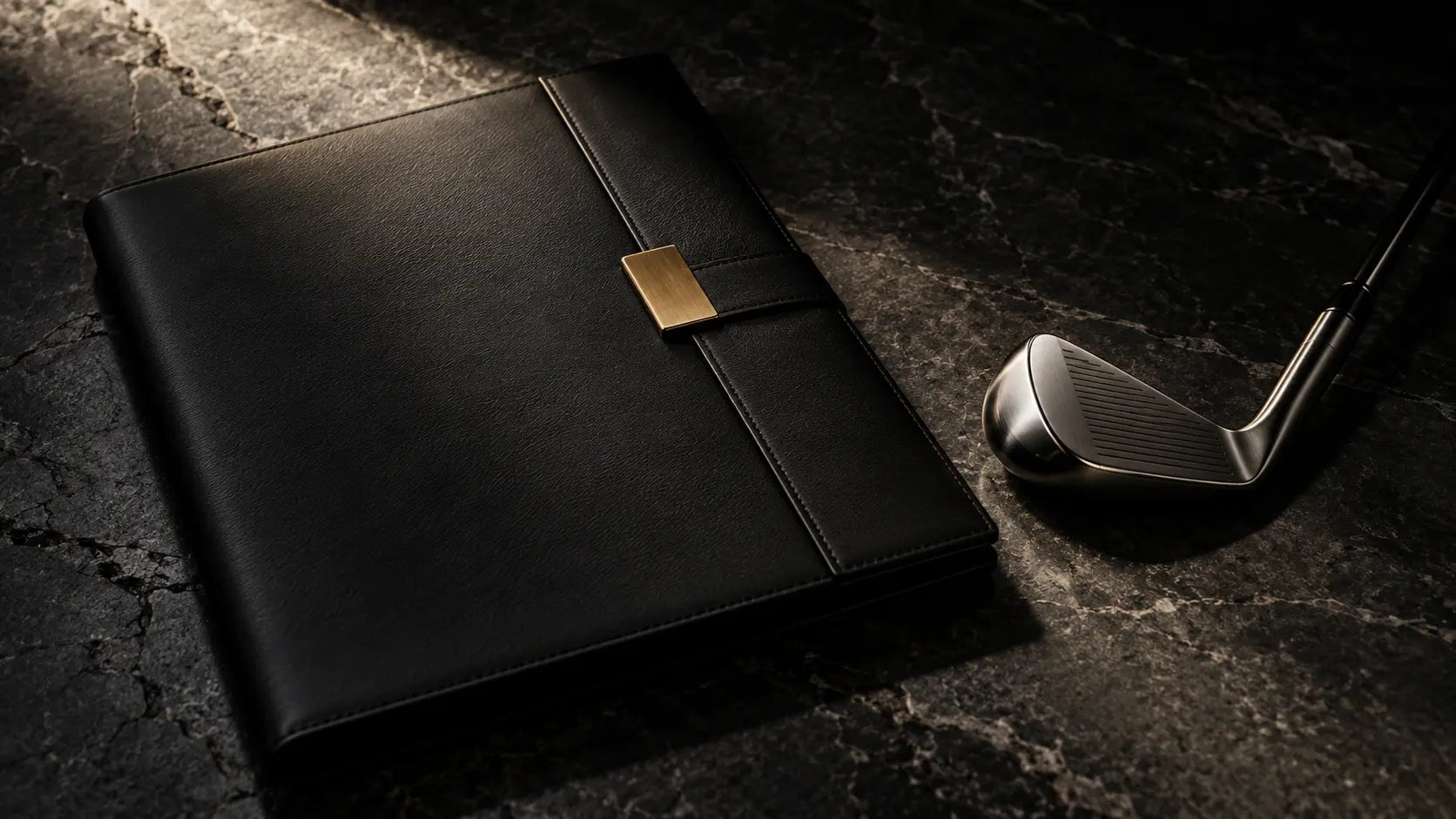 Black archival folio beside a forged golf club head